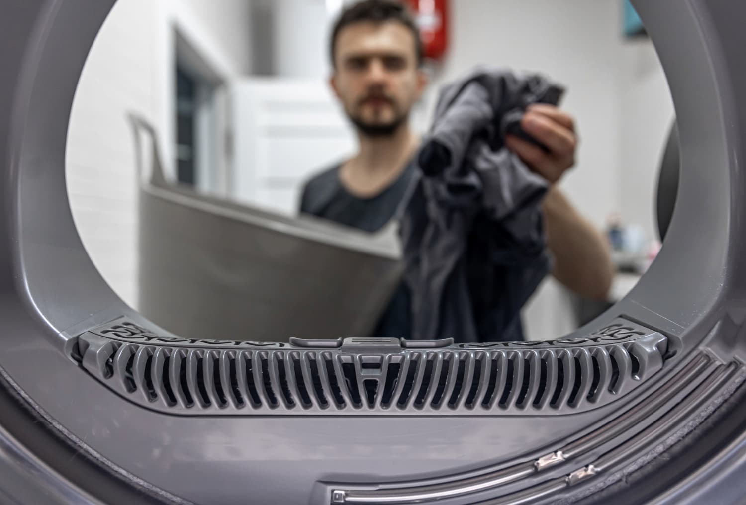 Die Waschmaschine stinkt? Diese einfachen Tipps helfen! Waschmaschine stinkt und Wäsche wird von Mann aus Maschine genommen